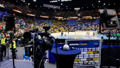 A professional camera setup captures a brightly lit indoor sports arena filled with spectators watching a game.